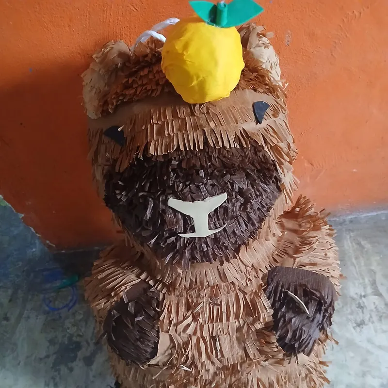 Piñata de capibara con una piña en la cabeza