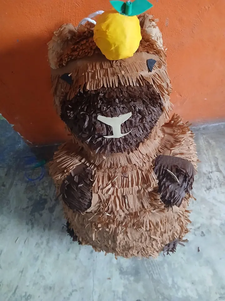 Piñata de capibara con una piña en la cabeza
