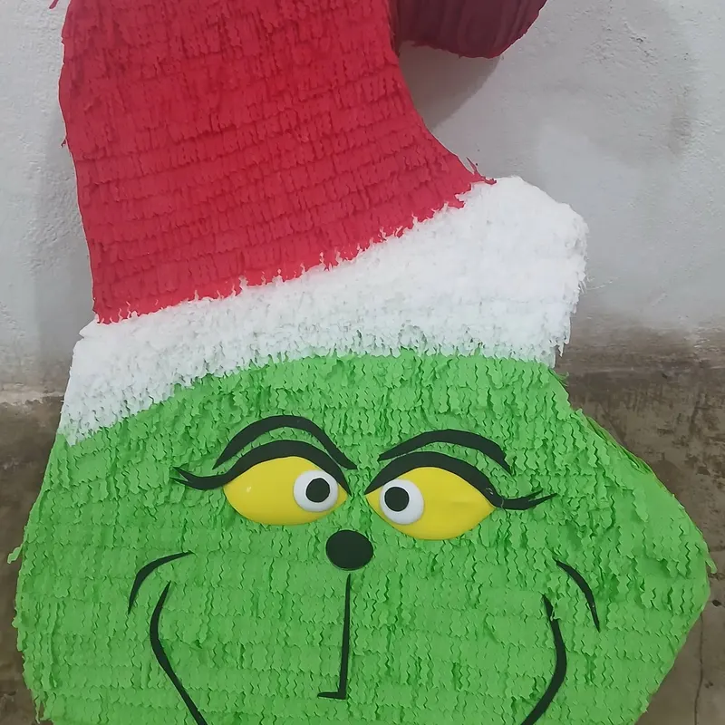 Piñata grande con el rostro del Grinch y gorro navideño