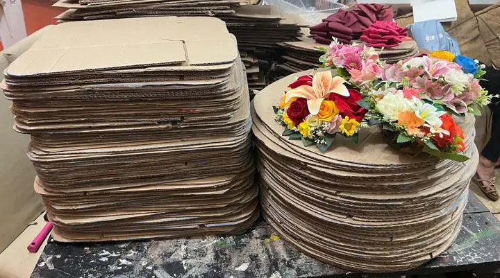Tapas de cartón apiladas junto a flores de tela