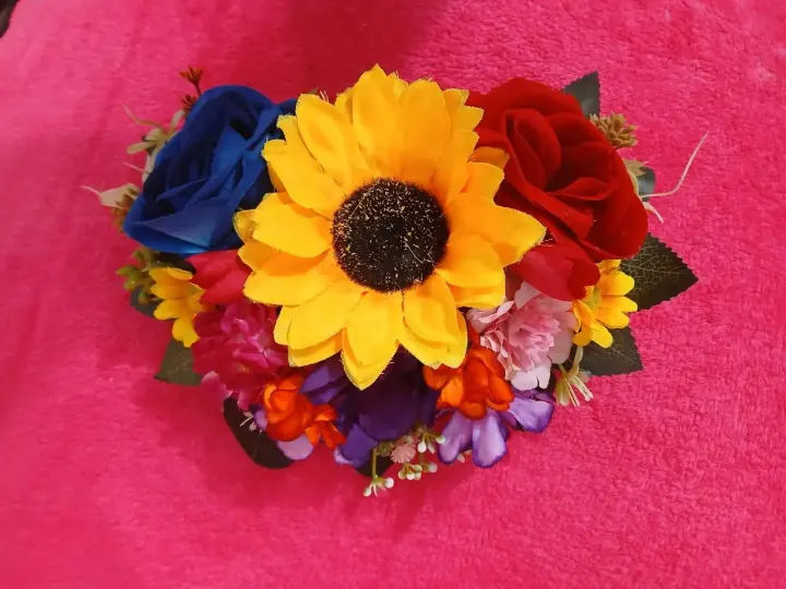 Tocado con un girasol grande y rosas azules y rojas